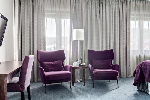 una habitación de hotel con 2 sillas moradas y una mesa en Best Western Plus Gyldenlove Hotell en Kongsberg