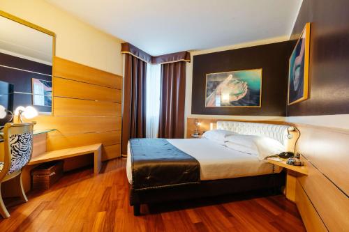 a hotel room with a bed and a desk and a mirror at Best Western Hotel Tre Torri in Altavilla Vicentina