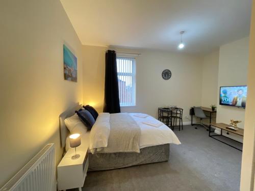 een slaapkamer met een bed, een bureau en een televisie bij Fogs Property - Darlington City Apartments in Darlington