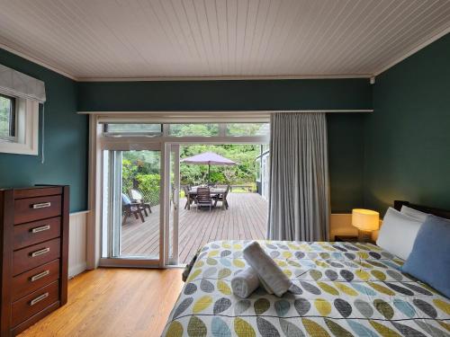 a bedroom with a bed and a patio with a table at Hot Water Beach Escape in Hotwater Beach