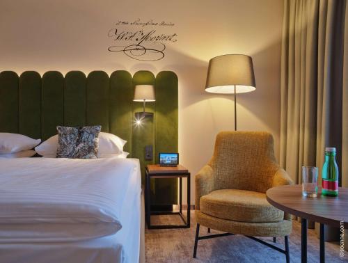 a hotel room with a bed and a chair and a table at Dorint City-Hotel Salzburg in Salzburg