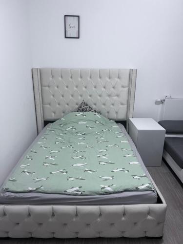 a bed with a green bedspread with white horses on it at Chambre individuelle dans un appartement à 37 de champs élysées in Sartrouville