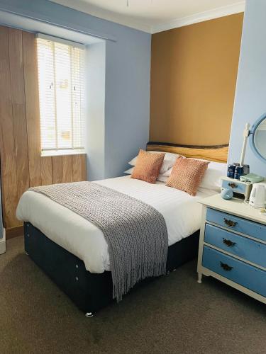 a bedroom with a large bed with a blue wall at Arosfa Harbourside Aberaeron in Aberaeron