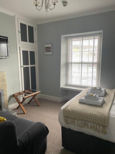 a bedroom with a bed and a couch and a window at Arosfa Harbourside Aberaeron in Aberaeron