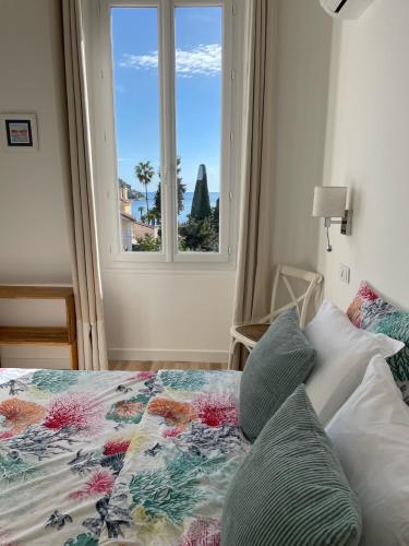 a bedroom with a bed with a window at Hôtel La Villa Patricia - Charme et Tradition in Villefranche-sur-Mer