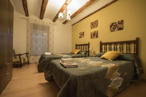 1 dormitorio con 2 camas y mantas verdes en Masía Nicolás, en Cella