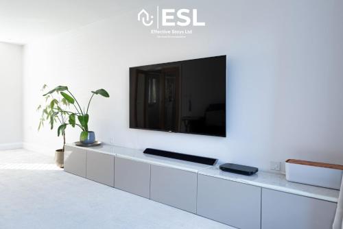a white cabinet with a tv on a white wall at Large Modern 4 Bedroom House in Uttoxeter, Near Alton Towers, Great for Families in Uttoxeter