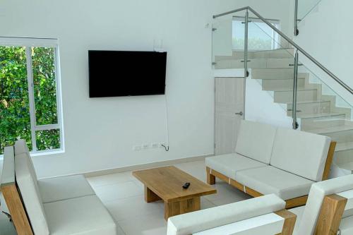 a living room with white furniture and a television at Condo Apulo - Hermosa casa - Jacuzzi y Piscina privados - WiFi in Apulo