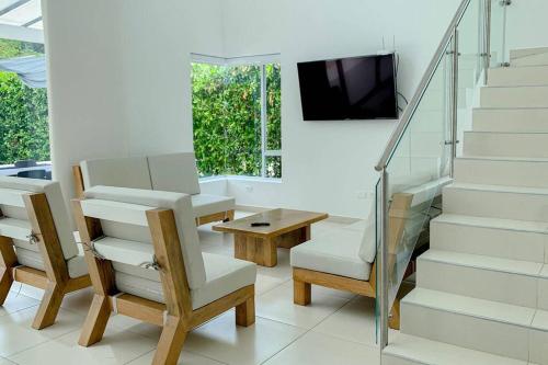 a living room with a table and a tv and stairs at Condo Apulo - Hermosa casa - Jacuzzi y Piscina privados - WiFi in Apulo