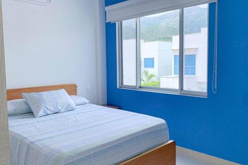 a blue bedroom with a bed and a window at Condo Apulo - Hermosa casa - Jacuzzi y Piscina privados - WiFi in Apulo