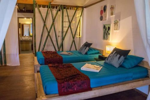 two beds in a room with blue sheets at Elnido Terra Nova beach resort Sunset Villa in El Nido