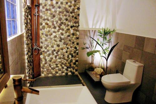 a bathroom with a toilet and a shower with a plant at Elnido Terra Nova beach resort Sunset Villa in El Nido