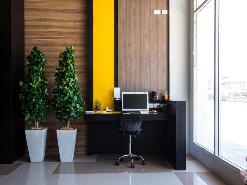 an office with a desk with a computer and two potted plants at Maison de Cheer in Trang