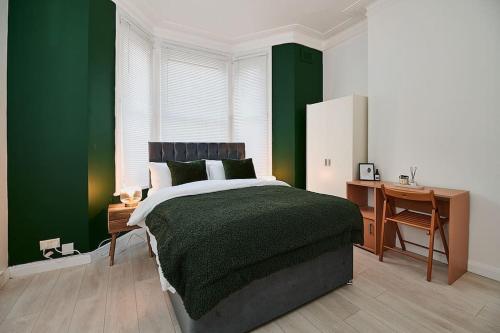 1 dormitorio con paredes verdes, 1 cama y escritorio en Fabulous 3 bed NW London apartment with private garden, en Londres