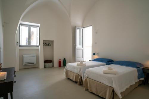 2 Betten in einem weißen Zimmer mit 2 Fenstern in der Unterkunft 1700's House with Panoramic Rooftop Terrace in Matino in Matino