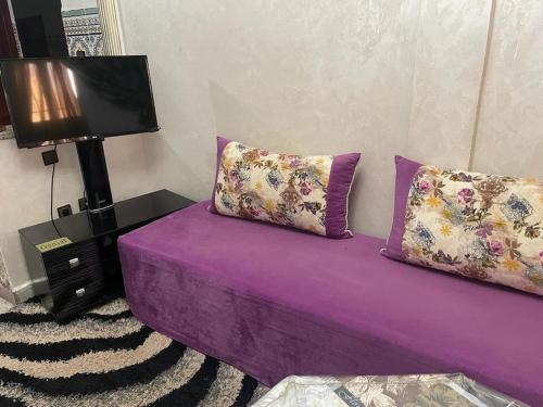 a purple couch with two pillows in a room at Residence el khannchi in Laayoune