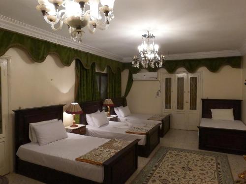 a bedroom with two beds and a chandelier at Grand Museum Guest House in Kafr Abū ʼumaydah