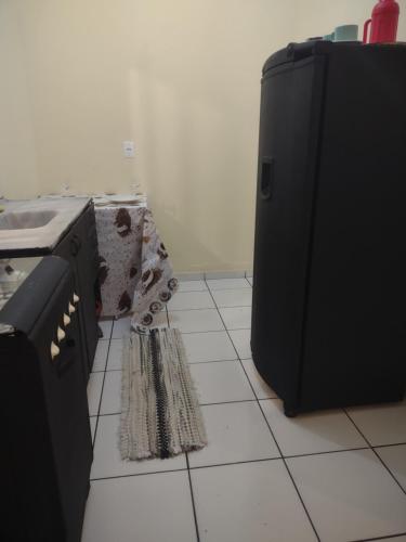 eine Küche mit einem schwarzen Kühlschrank und Fliesenboden in der Unterkunft Studio 33 próximo ao Centro in Palmas