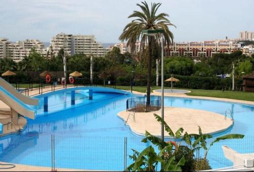 een groot blauw zwembad met een palmboom en gebouwen bij Benalmadena Jupiter Ocean View Apartament in Benalmádena