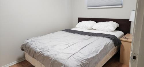 1 dormitorio con 1 cama con 2 almohadas en ChessKings Guest House - Unit 1, en Winnipeg