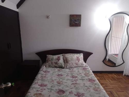 a bedroom with a bed with a floral bedspread and a mirror at Hotel Bogotá Calle 100 in Bogotá