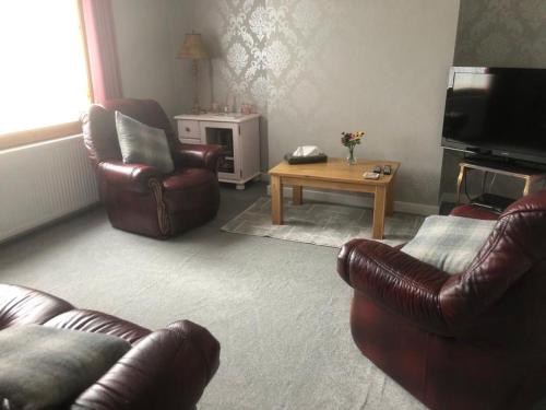 Sala de estar con 2 sillas de cuero y mesa de centro en Two Chimneys en Upper Bayble