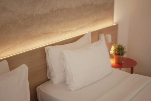 a white bed with white pillows and a table with a plant at Malaka Hotel Bandung in Bandung