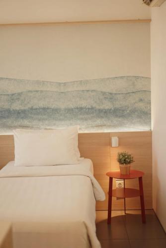 a bedroom with a bed and a painting of the ocean at Malaka Hotel Bandung in Bandung
