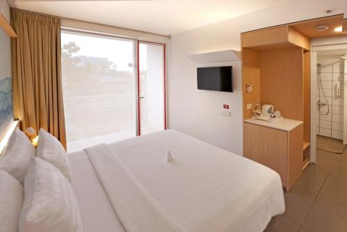 a bedroom with a white bed and a large window at Malaka Hotel Bandung in Bandung