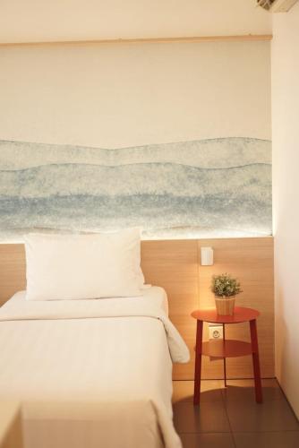 a bedroom with a bed and a painting of the ocean at Malaka Hotel Bandung in Bandung
