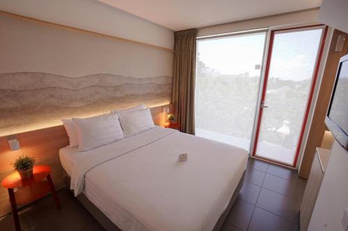a bedroom with a white bed and a large window at Malaka Hotel Bandung in Bandung