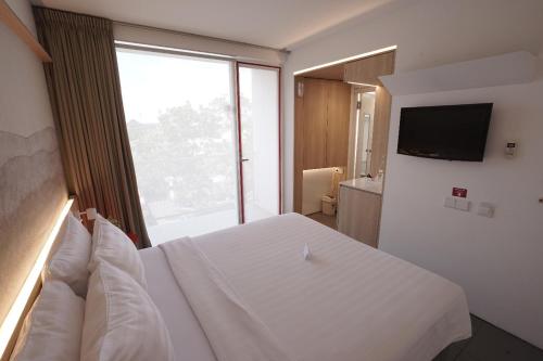 a bedroom with a white bed and a large window at Malaka Hotel Bandung in Bandung
