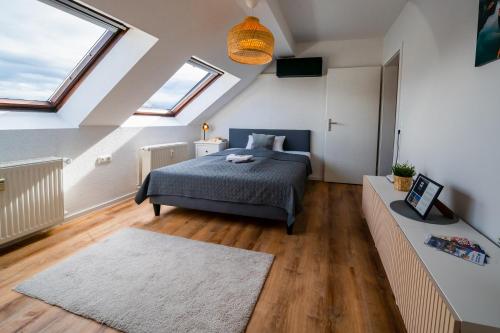 Schlafzimmer im Dachgeschoss mit einem Bett und zwei Fenstern in der Unterkunft STYLE-Apartment I Klimaanlage I WLAN I Küche I Smart-TV in Magdeburg