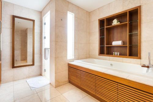 a bathroom with a tub and a sink and a mirror at Danang Villas Complex in Danang