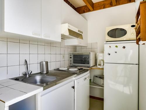 La cuisine blanche est équipée d'un évier et d'un réfrigérateur. dans l'établissement Appartement T3 duplex à 300m de la plage avec parking - FR-1-521-144, à Biscarrosse