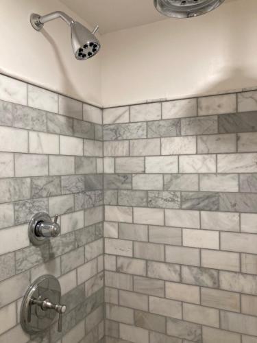 e bagno con doccia e piastrelle grigie e bianche. di Pineapple House, Cozy Garden Apartment, City Center! Marble-Tiled Bathroom! FREE parking! a Denver