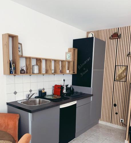une petite cuisine avec un évier et un réfrigérateur dans l'établissement Joli T2 à Dinard coeur de Saint Enogat, 200m de la plage, à Dinard