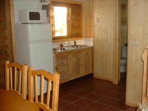 a kitchen with a white refrigerator and a sink at El Muerdago de Cañada in Cañada del Hoyo