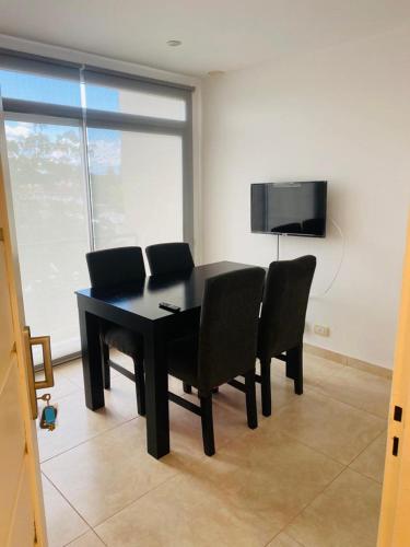 a black dining room table with chairs and a flat screen tv at Enjoy Apart Campana in Campana