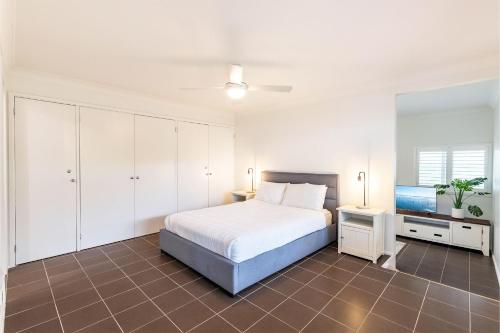 1 dormitorio blanco con 1 cama y TV en Shoalz Renovated Cottage and Boat Parking, en Shoal Bay