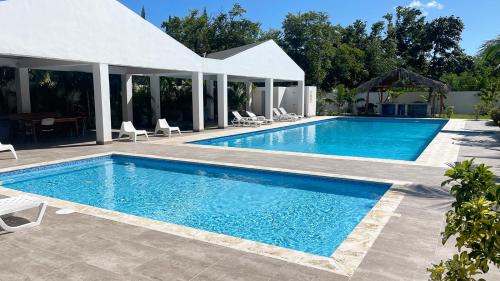een zwembad met blauw water voor een huis bij Precioso Apartamento a solo pasos de la Playa in Punta Cana