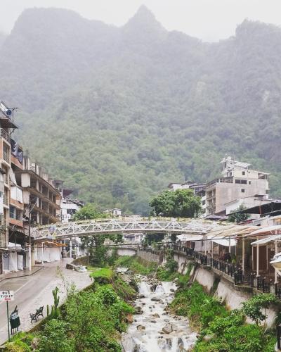 a bridge over a river with mountains in the background at Amakonkay Machupicchu in Machu Picchu