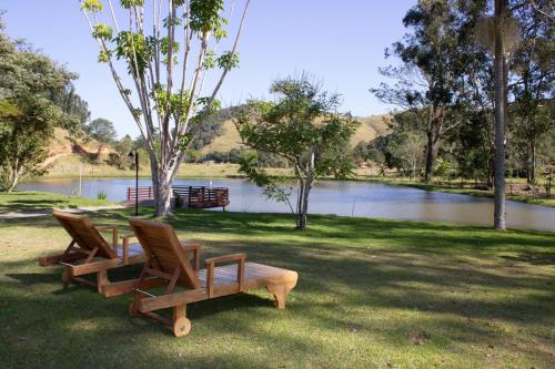 two chairs sitting in the grass next to a lake at POUSADA SERTÃO DA BOCAINA in Cunha