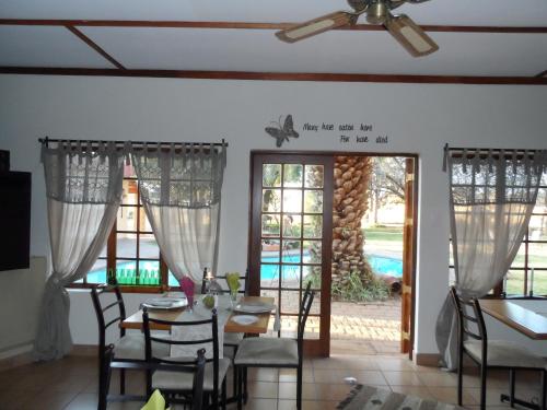 a dining room with a table and chairs and windows at A Cherry Lane Self Catering and B&B in Bloemfontein