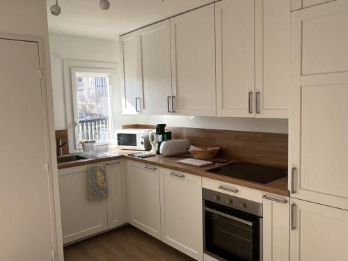 une cuisine blanche avec des armoires blanches et une fenêtre dans l'établissement Appartement 3 pièces avec terrasses et vue mer - Parking inclus - FR-1-487-349, à Cabourg