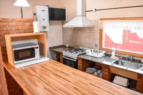 cocina con encimera y microondas en Cabañas Las Nubes en Puerto Deseado