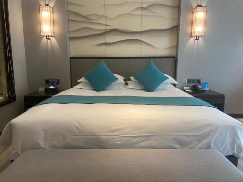 a bedroom with a large white bed with blue pillows at SSAW Boutique Hotel Lishui Jiarui in Lishui