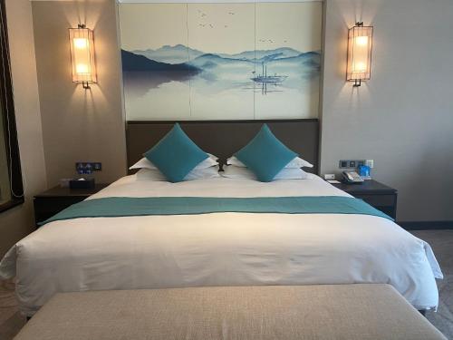 a bedroom with a large white bed with blue pillows at SSAW Boutique Hotel Lishui Jiarui in Lishui