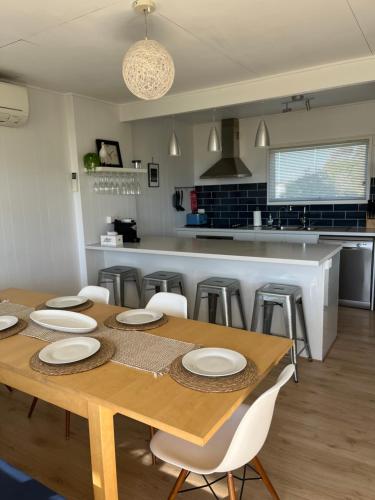 a kitchen with a wooden table with white plates on it at Aldinga Beach Break - C21 SouthCoast Holidays in Aldinga Beach