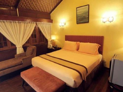 Shah's Beach Resort Melaka في ميلاكا: غرفة نوم بسرير وكرسي وأريكة